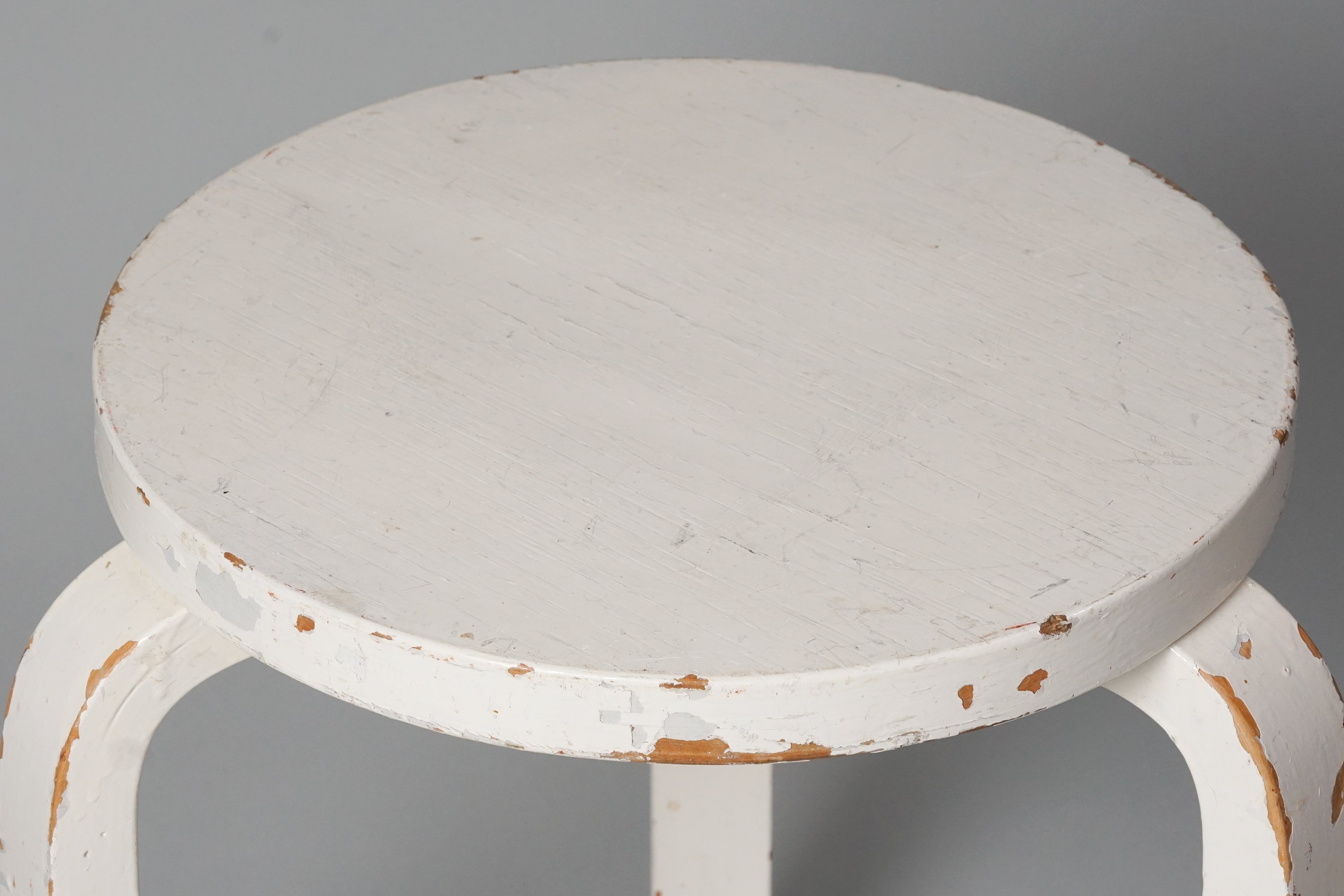 Three legged stool made of birch with a round seat. The stool is painted white.